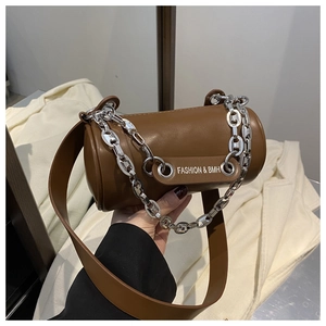 Détail d'un sac cylindrique caramel avec chaîne en métal argenté et étiquette tendance