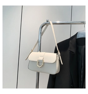 Detail of elegant ivory shoulder bag featuring a silver U-shaped metal clasp and leather strap