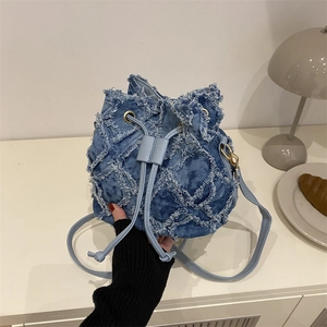 Blue denim drawstring bucket bag featuring quilted frayed edges and leather shoulder strap