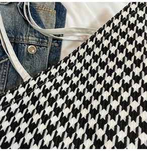 Macro detail of high-quality houndstooth fabric texture on a large shoulder tote bag