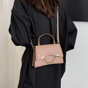 Sac à bandoulière rose nude élégant avec chaîne dorée et poignée sur un modèle