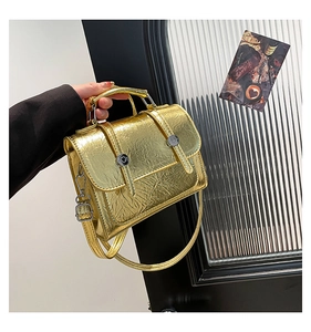 Close-up of golden metallic pleated small square bag with vintage buckles and crossbody strap