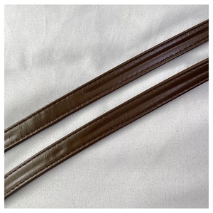 Close-up of brown leather bag straps featuring precise stitching on a gray surface