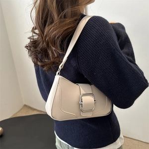Sac baguette minimaliste blanc cassé avec boucle argentée porté par un mannequin en pull bleu