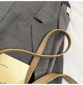 Close-up of litchi-grain leather strap stitching on a gray textured suit fabric