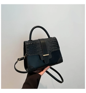 Detail of black crocodile texture patchwork handbag with gold clasp and top handle