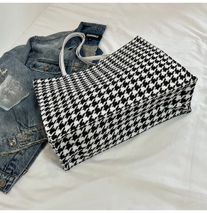 Detail of classic black and white houndstooth canvas tote bag with slim white handles