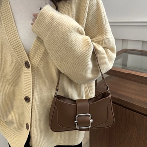 Sac baguette minimaliste en cuir marron avec boucle argentée porté par un mannequin chic