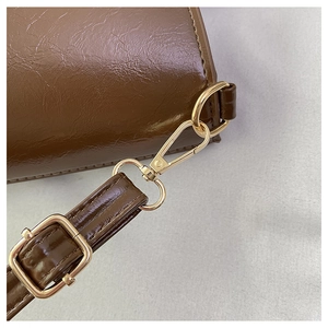 Detail of dark brown leather bucket bag with adjustable golden metal buckle and hardware