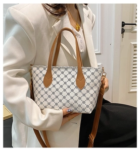 Detailed view of fashionable checkered tote bag with brown leather straps and gold hardware