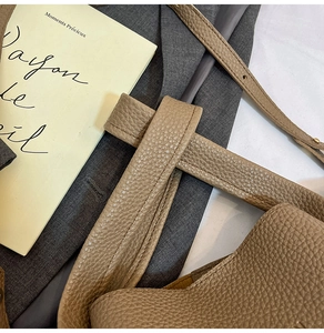 Detail of the thick lychee pattern leather handle with precise stitching on a khaki tote