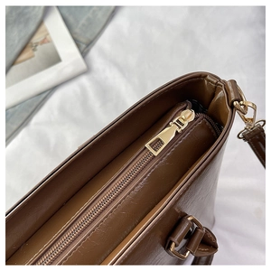 Detailed close-up of premium dark brown leather bucket bag with gold metal zipper hardware