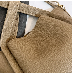 Close-up of khaki lychee leather bucket bag featuring embossed FASHION logo and texture