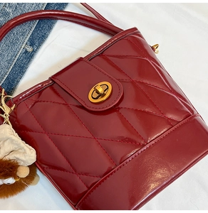 Détail du sac seau bordeaux matelassé avec fermoir doré et breloque peluche