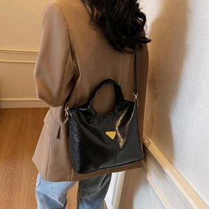 Minimalist black shiny bucket bag for women with gold logo and crossbody strap