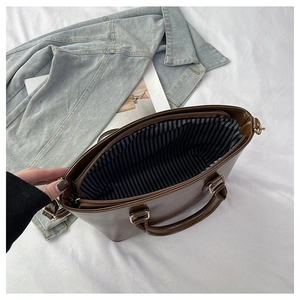 Top view of large brown faux leather tote bag with striped lining and zipper closure