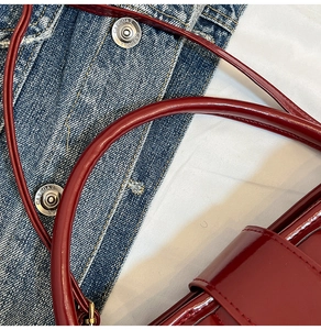 Détails du sac seau en cuir verni bordeaux avec finition brillante et coutures de luxe