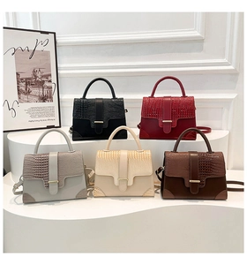 Collection of five croc-embossed trapezoid handbags in various colors on display