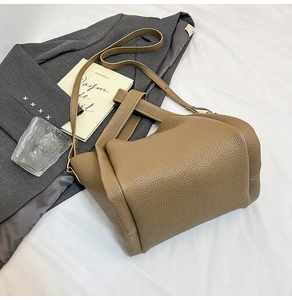 Detailed view of dark brown litchi grain leather bag with wide strap and gold hardware
