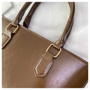 Detailed macro view of dark brown textured leather bucket bag with gold hardware and stitching