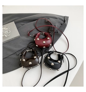 Close-up of micro crescent rivet bags in burgundy, brown and black on a grey blazer