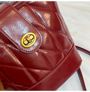 Détail du sac seau bordeaux avec surpiqûres en losanges et fermoir rotatif doré