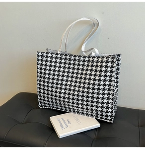 Macro detail of classic houndstooth weave texture and sturdy white shoulder strap on tote bag