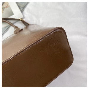 Detail shot of vintage dark brown bucket bag showing glossy leather texture and stitching