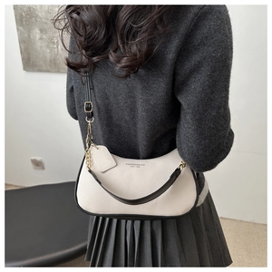 Detail of white crescent bag with lychee texture and black leather trim for women