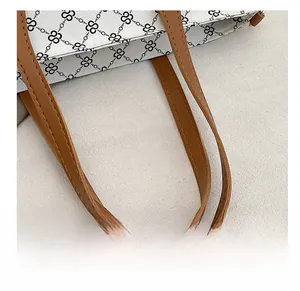 Close-up of brown leather handles with durable double stitching on a geometric tote bag