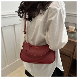 Detail of red pebble grain leather underarm bag with gold chain and fashion lettering