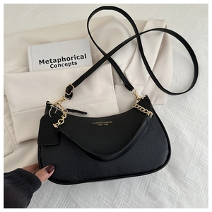 Detail of black pebbled leather crossbody bag with gold chain and fashion lettering