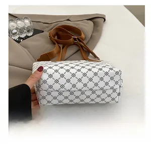 Detail showing durable fabric bottom and brown nylon strap of checkered tote bag
