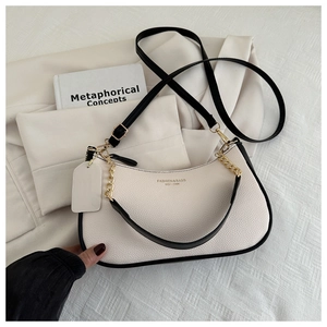 Close-up of beige lychee leather crescent bag with golden chain and adjustable strap