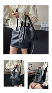 Detail of black lychee grain leather bucket bag featuring a detachable shoulder strap