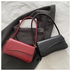 Flat lay of red and black minimalist leather crescent flap bags on a grey suit jacket