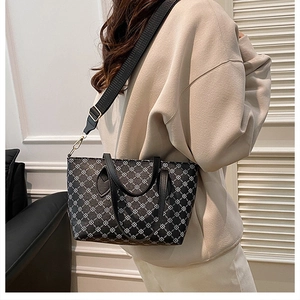 Detail view of large grey tote bag with white geometric clover patterns and black straps