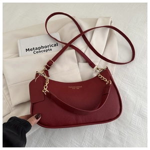 Macro shot of burgundy pebble leather shoulder bag with gold chain and brand logo