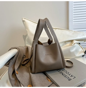 Detail of taupe lychee pattern leather bucket bag with embossed Fashion logo and wide handle