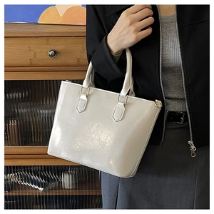 Detail view of white glossy leather bucket bag with elegant golden hardware accents