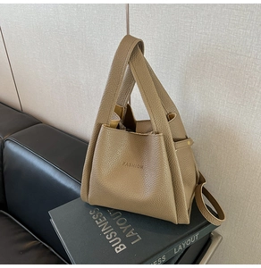 Close-up of khaki litchi grain leather bucket bag with FASHION embossed detail