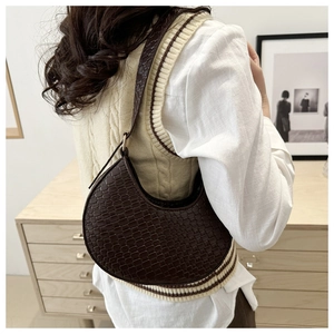 Detail of a dark brown crescent bag showing the weave texture and adjustable shoulder strap