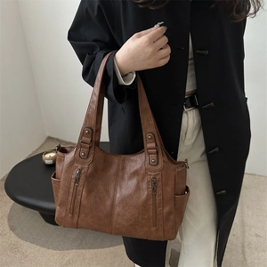 Sac cabas en cuir marron avec zips verticaux présenté dans un décor intérieur épuré