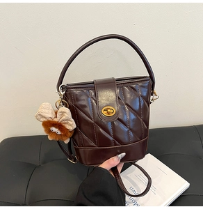 Détail du sac seau matelassé marron foncé avec fermoir doré et pendentif peluche