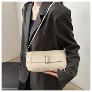 Detail view of a cream leather baguette shoulder bag with a silver buckle on a grey blazer