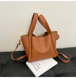 Close-up of brown lychee leather tote bag featuring debossed FASHION text and long strap