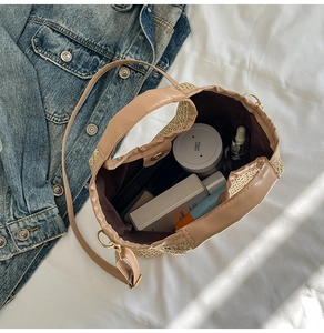 Top view of woven straw bucket bag showing interior space with cosmetics and brown lining