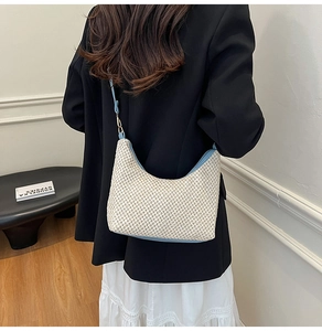 Detail of hand-woven beige straw texture and light blue leather trim on half-moon bag
