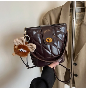 Détail du sac seau matelassé marron foncé avec fermoir doré et pendentif en peluche