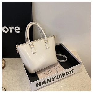 Detail of white matte leather tote bag with gold hardware inside a white box